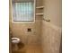 A bathroom with a tiled floor and walls, shelves and a window at 2436 Glenrock Dr, Decatur, GA 30032
