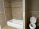 Neutral tiled bathtub and toilet in cozy bathroom at 2436 Glenrock Dr, Decatur, GA 30032