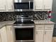 Close up of kitchen appliances including Samsung stove top and microwave, granite countertops, and tile backsplash at 2436 Glenrock Dr, Decatur, GA 30032