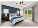 Well-lit carpeted bedroom features a blue accent wall, ceiling fan, and dual windows for natural lighting at 65 Harmony Woods Ln, Dallas, GA 30157