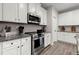 Detailed view of the kitchen featuring white cabinets, stainless steel appliances, granite countertops, and wood flooring at 65 Harmony Woods Ln, Dallas, GA 30157