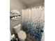 Bathroom featuring a toilet and a shower with white and blue patterned curtain and circular sea-themed painting at 2030 Hydrangea Ln, Austell, GA 30106
