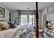 A bedroom featuring a four-poster bed with decorative pillows and duvet cover, plus bright windows and vintage décor at 3621 Portland Trail Dr, Suwanee, GA 30024