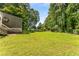 Lush green backyard with trees and a house with a lake view, blending nature and comfortable living at 5219 Legendary Ln, Acworth, GA 30102