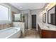 Bathroom with tile surround on garden tub, glass shower, and double vanity at 1374 Highland Wood Ct, Auburn, GA 30011
