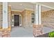 Close-up view of a covered front porch with stone-clad columns and a brick facade at 1374 Highland Wood Ct, Auburn, GA 30011