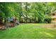 Expansive backyard featuring a playset, lush green lawn, and mature trees at 9685 Cone Ct, Roswell, GA 30075