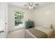 Bright bedroom with a single bed, blue chest of drawers, ceiling fan, and a large window view at 9685 Cone Ct, Roswell, GA 30075