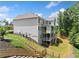 Exterior view showcases the home's backyard, featuring a deck and a landscaped hillside at 127 Sanctuary Ave, Woodstock, GA 30188