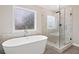 Modern bathroom with a freestanding tub, glass shower, and decorative window at 127 Sanctuary Ave, Woodstock, GA 30188