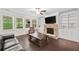 Comfortable living room featuring a stone fireplace, built-ins, and windows that provide plenty of natural light at 127 Sanctuary Ave, Woodstock, GA 30188