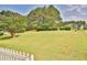 Expansive grassy front yard with a quaint white picket fence, lush trees, and a home in the background at 501 Grace Ct, Temple, GA 30179