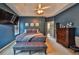 A bright main bedroom features a tray ceiling with ceiling fan, sitting bench and large dresser at 501 Grace Ct, Temple, GA 30179