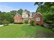 Beautiful two-story brick home with manicured lawn, mature trees, and classic architectural details at 1920 Lee Patrick Dr, Dacula, GA 30019