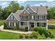 Elegant brick home features a well-manicured lawn, lush landscaping, and a covered front porch at 107 Equest Dr, Canton, GA 30115