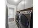 Laundry room with gray cabinets, stainless steel washer and dryer, and gray tile flooring at 107 Equest Dr, Canton, GA 30115