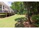 A large backyard with mature trees, lush green grass, and a deck at 1564 Stepstone Way, Lawrenceville, GA 30043