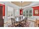 Formal dining room with red walls, white trim, and a large window offering natural light, adjacent to the living room at 1564 Stepstone Way, Lawrenceville, GA 30043