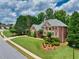 Beautifully landscaped brick home with a lush green lawn, mature trees, and a circular driveway in a suburban setting at 1564 Stepstone Way, Lawrenceville, GA 30043