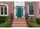 Inviting front entrance with a green door, brick steps, black wrought-iron railings, and well-maintained landscaping at 1564 Stepstone Way, Lawrenceville, GA 30043