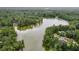 Aerial view highlighting a tranquil lake with houses nestled among the surrounding trees at 212 Teepee Trl, Whitesburg, GA 30185