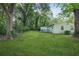 Expansive backyard with lush green lawn and mature trees surrounding a charming green home with a blue deck at 390 Lincoln Sw Pl, Atlanta, GA 30315