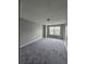 An empty bedroom with neutral walls, plush gray carpet, and a window offering natural light at 2612 Haligan Pt, Riverdale, GA 30296