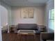 Cozy living room featuring modern gray furniture, wood floors, and ample natural light from the window at 2647 Old Snapping Shoals Rd, Mcdonough, GA 30252