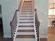 Staircase with wooden handrail leads to the second floor with adjacent view of kitchen at 2647 Old Snapping Shoals Rd, Mcdonough, GA 30252