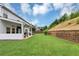 Backyard view featuring lush green grass, a covered patio, and a retaining wall at the edge of the property at 226 Creek View Ln, Acworth, GA 30102