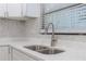 Close-up of a stainless steel kitchen sink, faucet, countertops, backsplash, and window with blinds at 4922 Glenside Ct, Stone Mountain, GA 30088