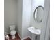Cozy powder room with a pedestal sink, round mirror, and wood-look floors at 210 Morning Dove Ln, Suwanee, GA 30024