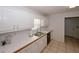 This well-lit kitchen offers white cabinetry, tile flooring, and a stainless steel sink overlooking the yard at 940 Sandy Ford Rd, Social Circle, GA 30025