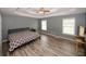 Large main bedroom featuring wood-look flooring, ceiling fan, and natural light from two windows at 940 Sandy Ford Rd, Social Circle, GA 30025