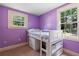 Charming bedroom with purple walls and a loft bed, illuminated by natural light from two windows at 433 Pine Dr, Pine Lake, GA 30072