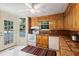 Sunlit kitchen with stainless steel sink, tiled countertops, white appliances, and door to outside at 433 Pine Dr, Pine Lake, GA 30072