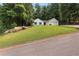View of a white house with blue shutters, a green lawn, and mature trees surrounding the property at 506 Bluff Ct, Woodstock, GA 30188