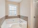 A white garden tub is surrounded by neutral tile beneath a window at 1001 Dunning Se St, Atlanta, GA 30315