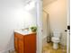 Bright bathroom featuring a wooden vanity, large mirror, toilet, and shower with neutral tiling at 1076 Scenic Park Trl, Lawrenceville, GA 30046