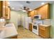 A kitchen featuring light wood cabinets, neutral countertops, white appliances, and a ceiling fan for optimal ventilation at 115 Pinnacle Ln, Mcdonough, GA 30253
