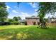 Expansive backyard with lush lawn, mature trees, playset and brick home exterior at 385 Stonebridge Trl, Roswell, GA 30075