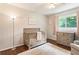 Bedroom room with hardwood flooring, crib, dresser, soft rug, and large window at 385 Stonebridge Trl, Roswell, GA 30075