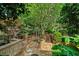 Well-maintained backyard with stone pathway, brick retaining wall, iron fence, and lush trees at 1344 Fernwood Ne Cir, Brookhaven, GA 30319