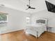 Bright bedroom featuring hardwood floors, a ceiling fan, and windows with wooded views at 3042 Oak Vista Way, Lawrenceville, GA 30044
