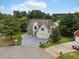 Aerial view of a two-story home with stone accents, attached two-car garage, driveway and treed yard at 3042 Oak Vista Way, Lawrenceville, GA 30044