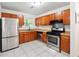 Well-equipped kitchen with stainless steel appliances, wood cabinets, and white tiled flooring at 3799 Henry Ct, Acworth, GA 30101