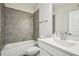 Well-lit bathroom features white fixtures and gray tiled shower with white shower tub at 20056 Windalier Way, Roswell, GA 30076