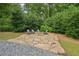 Secluded fire pit with stone surround and seating, enveloped by lush greenery, for cozy gatherings at 20056 Windalier Way, Roswell, GA 30076