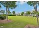A view of neighborhood homes bordering large green space and mature trees under blue sky at 20056 Windalier Way, Roswell, GA 30076