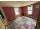 Bedroom with two windows, pink walls, and damaged floors at 3700 Moore Rd, Austell, GA 30106